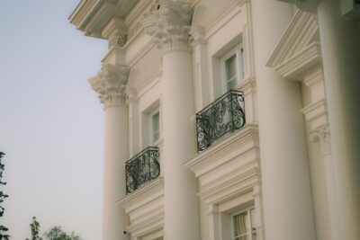 Close-up of a neoclassical building facade featuring large white columns and decorative ironwork balconies.
